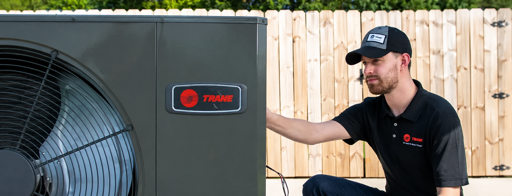 HVAC technician inspecting a Trane air conditioning system at a residential home